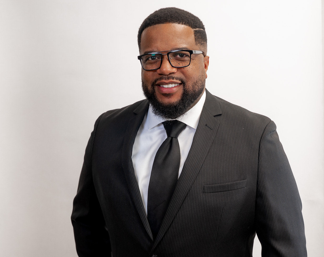 Man wearing a black suit and tie against a white background